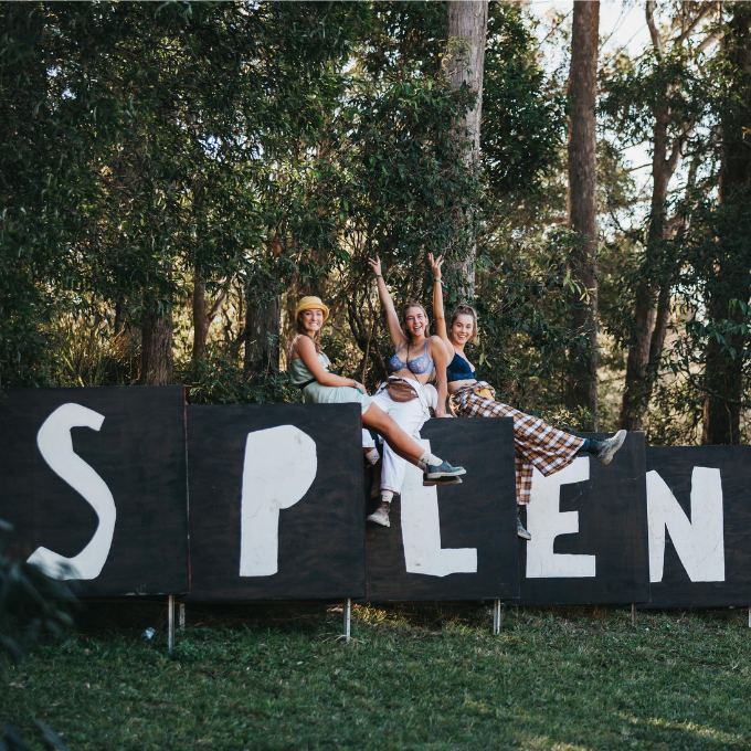 Friends sitting on a sign that reads Splendour