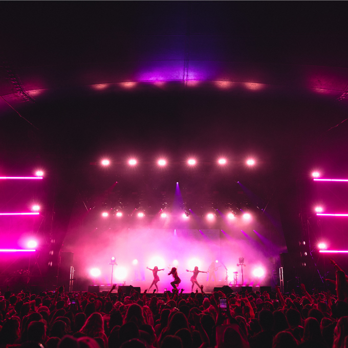 An artist performing on stage at Splendour with pink lighting