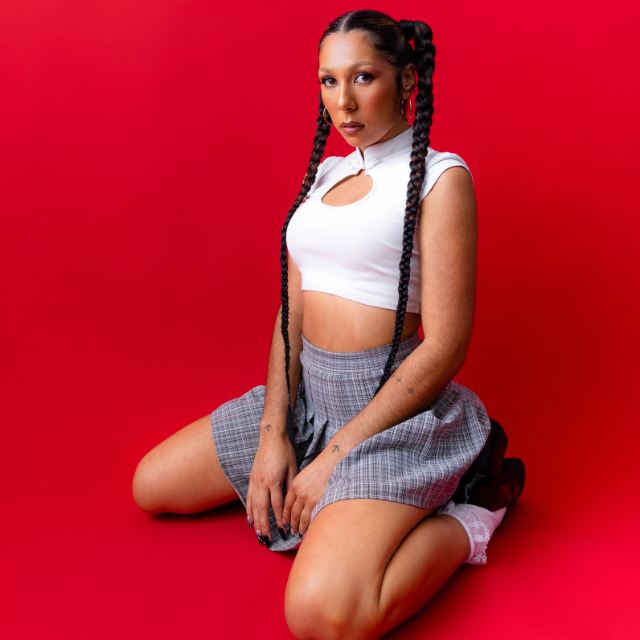 Miss Kaninna crouching in front of a red backdrop