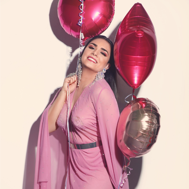 Victoria Anthony in a pink dress holding the pink balloons.